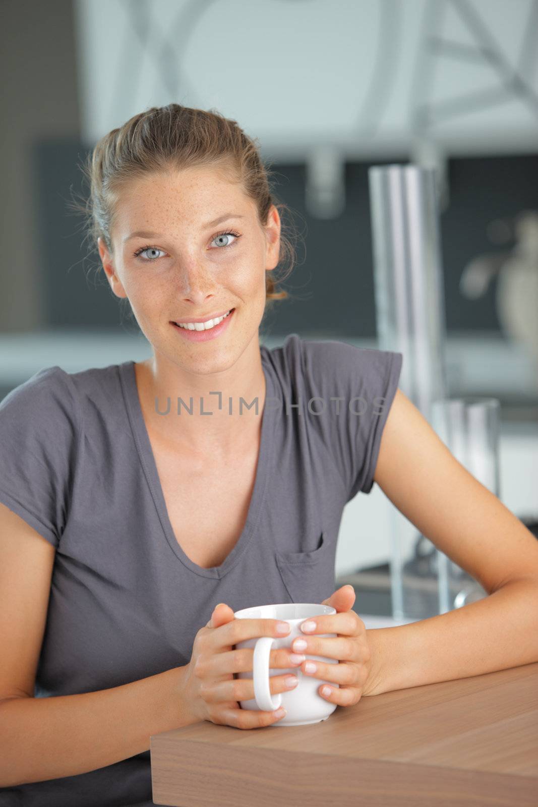 Beautiful girl in kitchen with a cup of cofee or tea