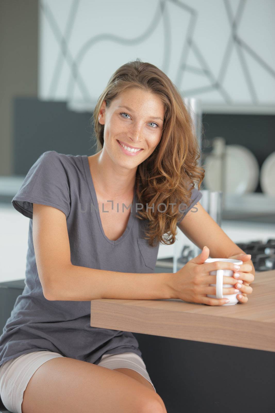 Beautiful girl in kitchen with a cup of cofee or tea