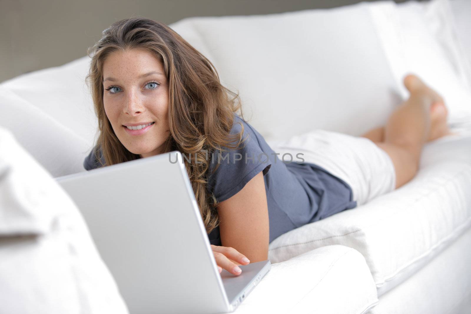 Pretty woman lying on sofa with laptop