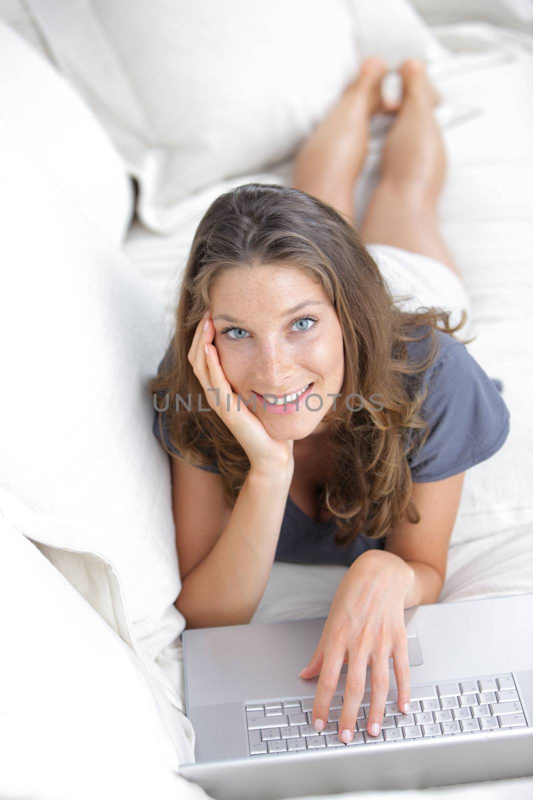 Portrait of a smiling woman browsing on her laptop indoors