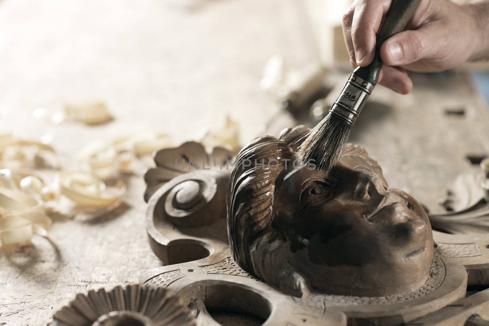 Close Up of carpenter apply varnish to a wooden sculpture