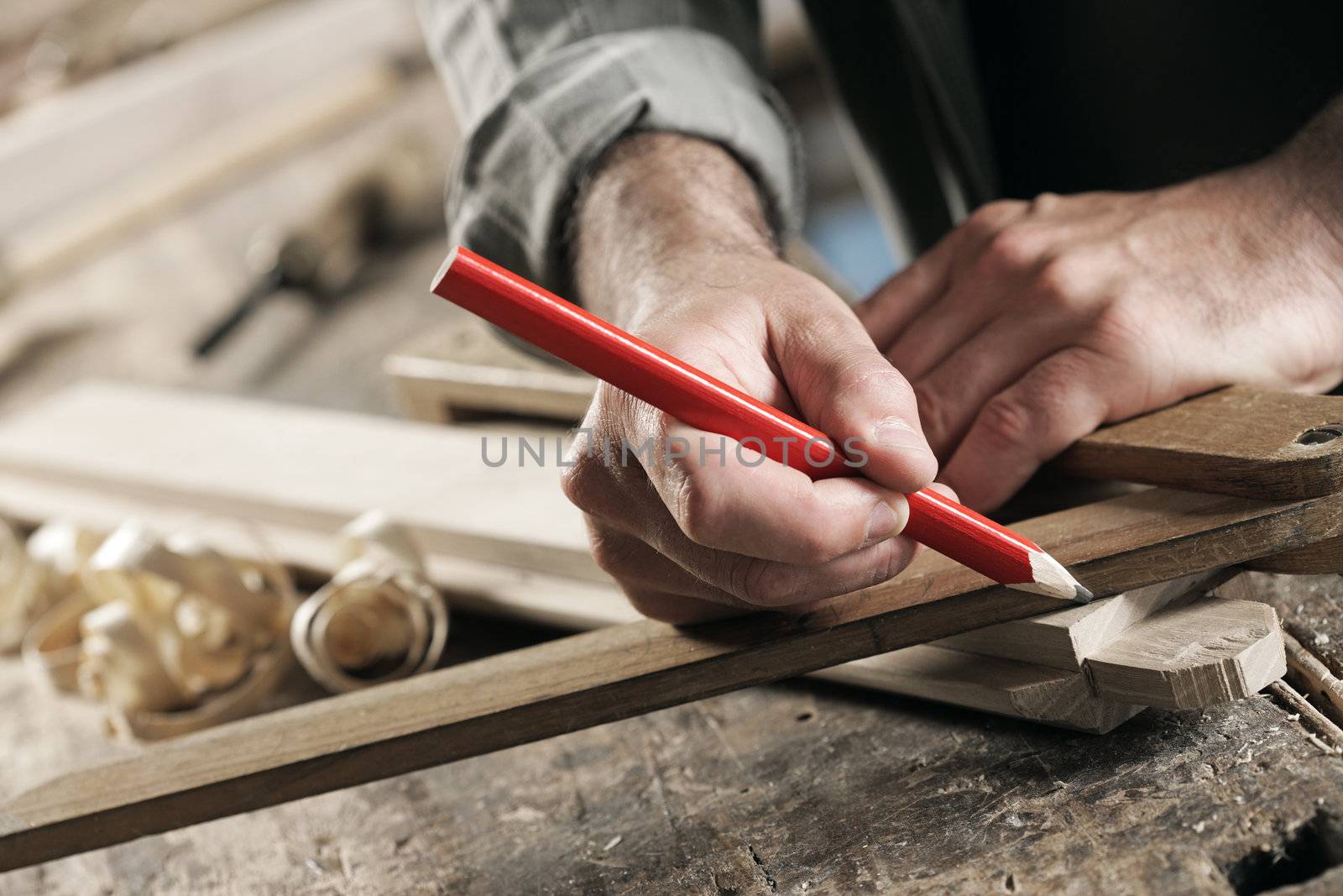 Close Up view of a carpenter using a straightedge to draw a line on a board.