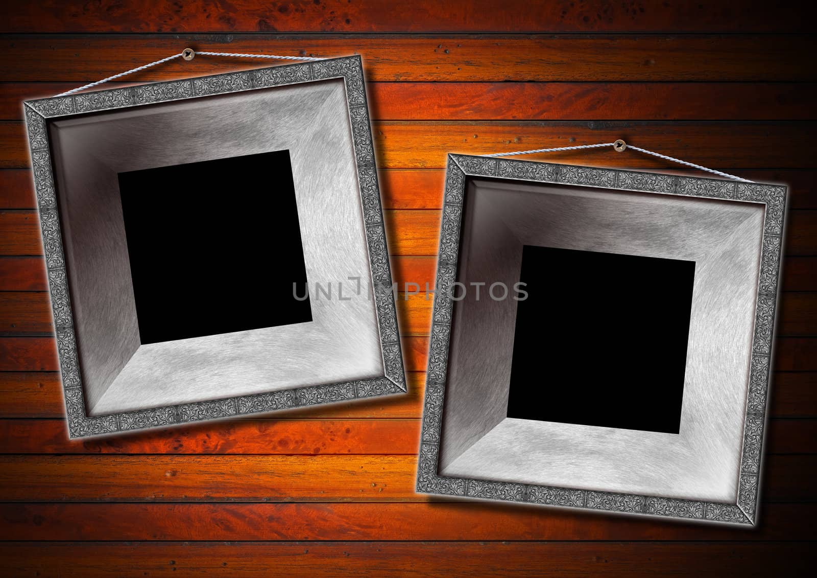 Two empty metallic frames on a old dark wooden wall
