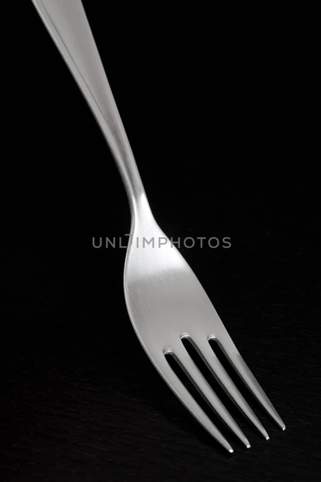 Elegant silver fork from 70s, on dark background.