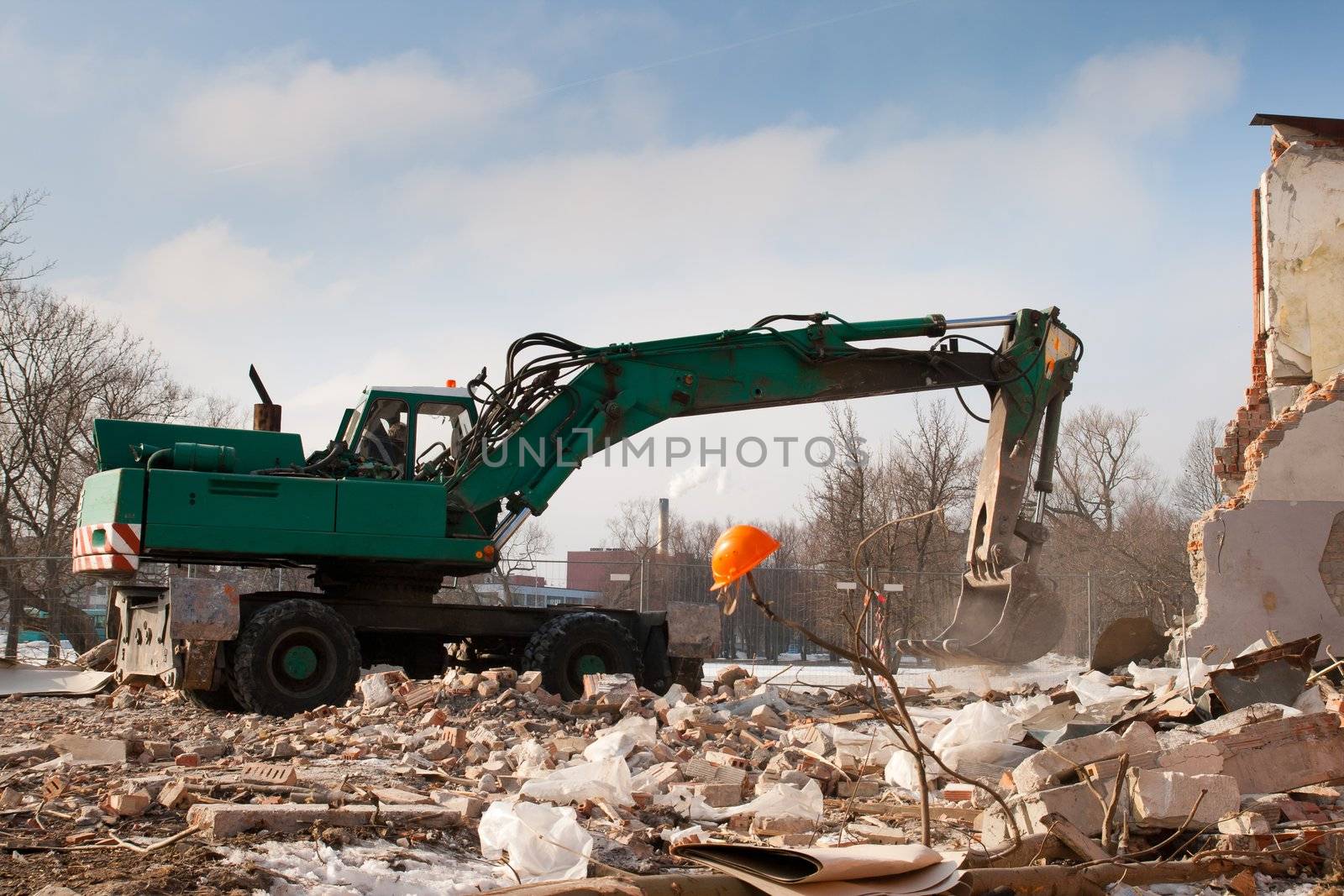 green excavator demolished an abandoned house in construction site