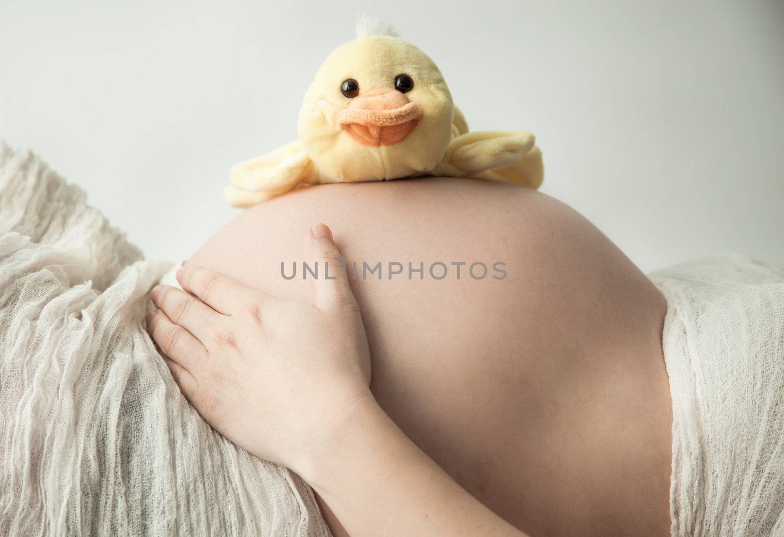 Pregnant belly lying with small duck by Izaphoto