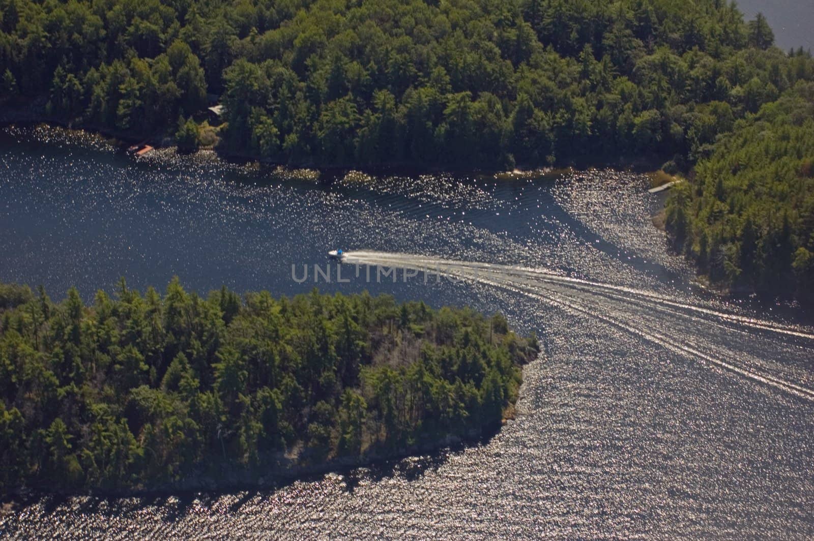 Small boat tracks on surface of water in sunlit