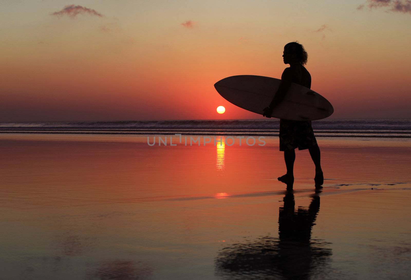 Silhouette of surfer with a board on a sunset