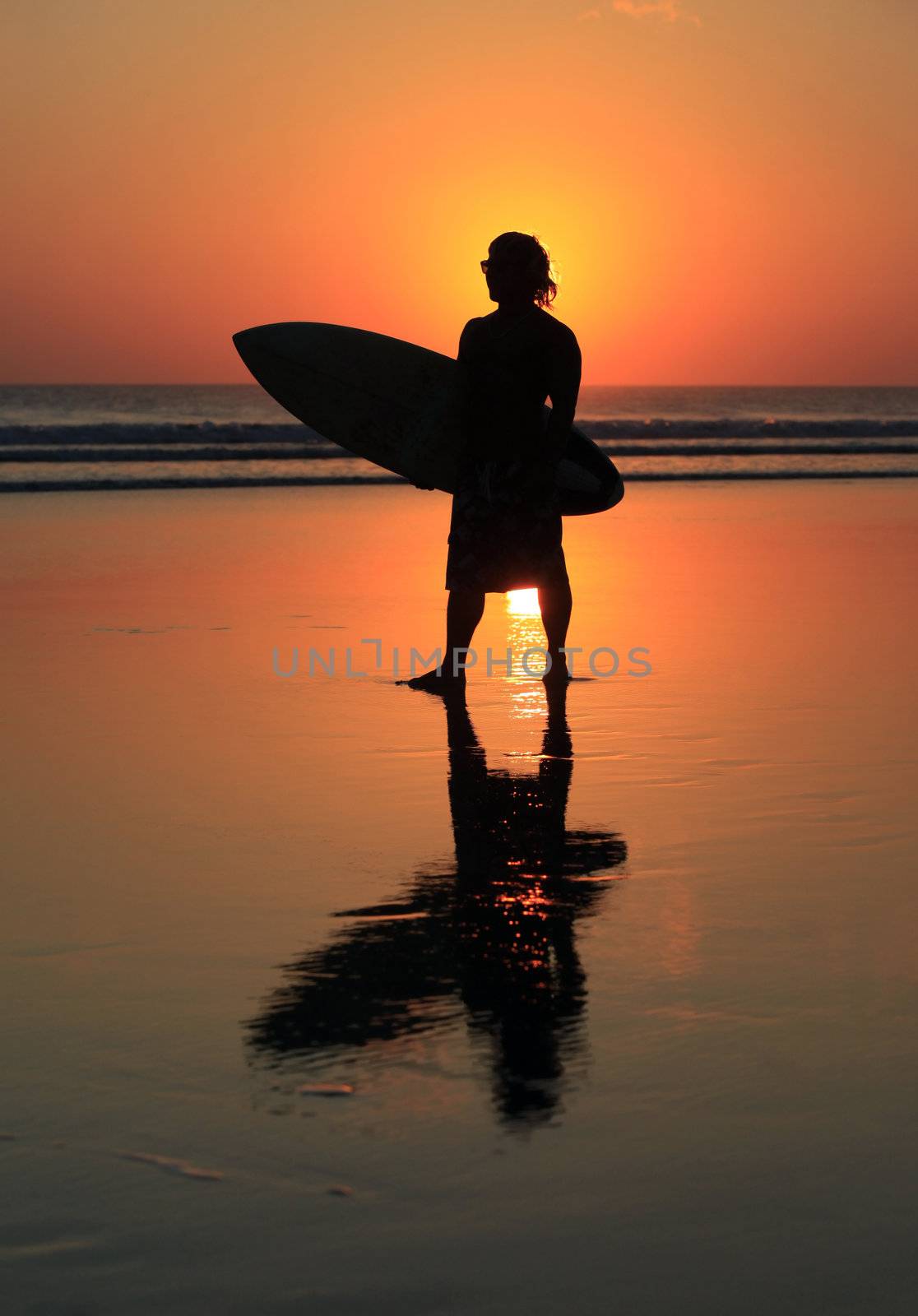 Silhouette of surfer with a board on a sunset
