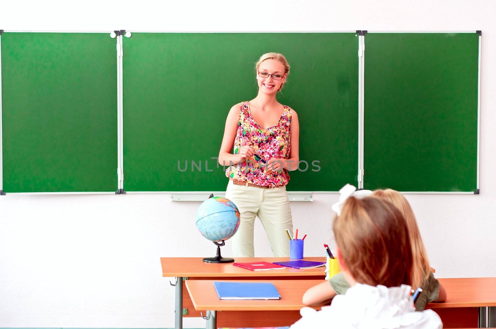 beautiful young woman standing at the blackboard and tells students a lesson