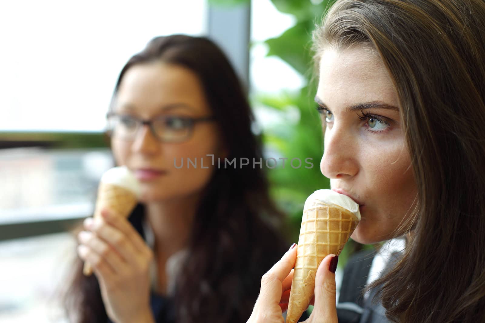 happy smiling women on foreground licking ice cream 