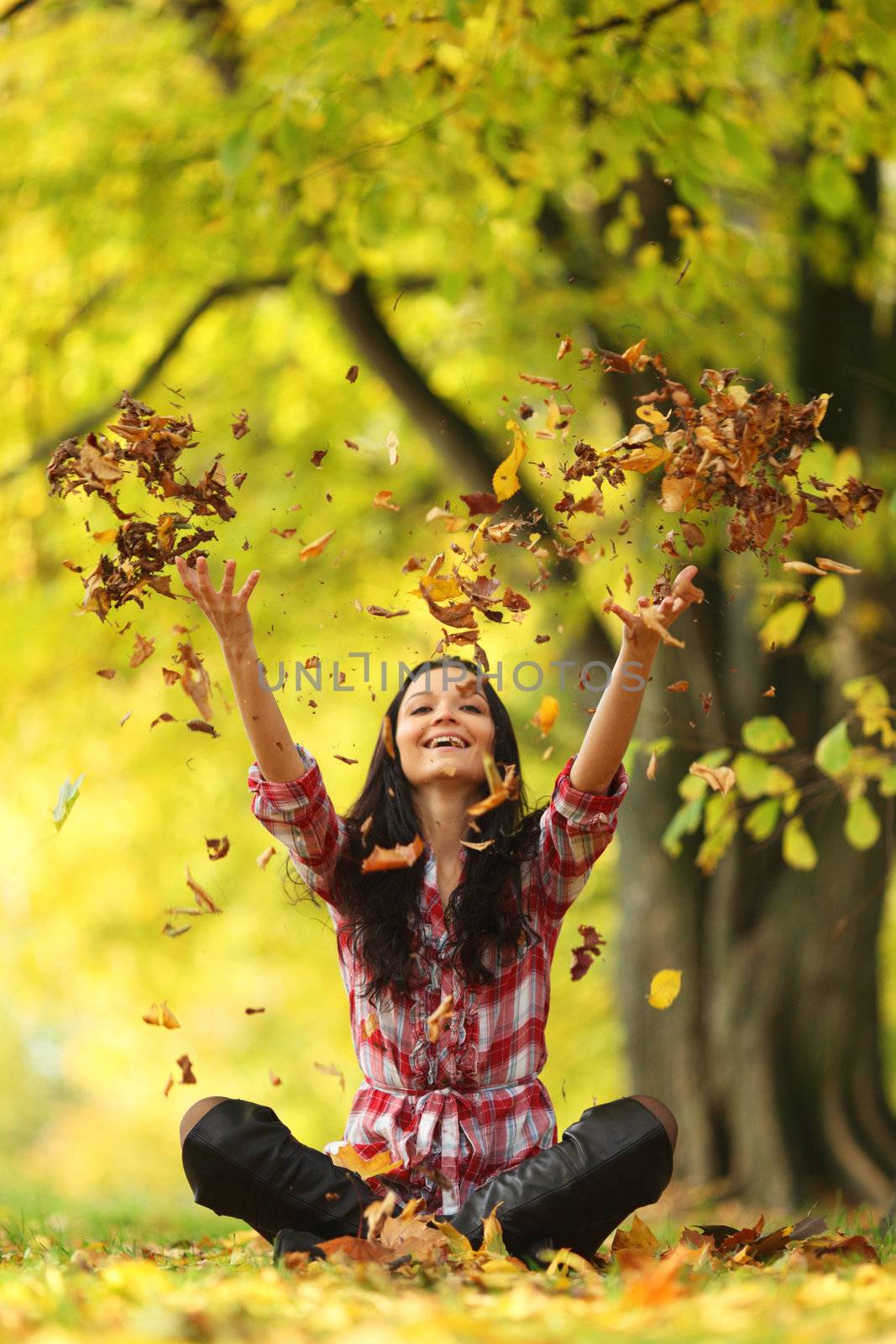 woman drop up leaves in autumn park