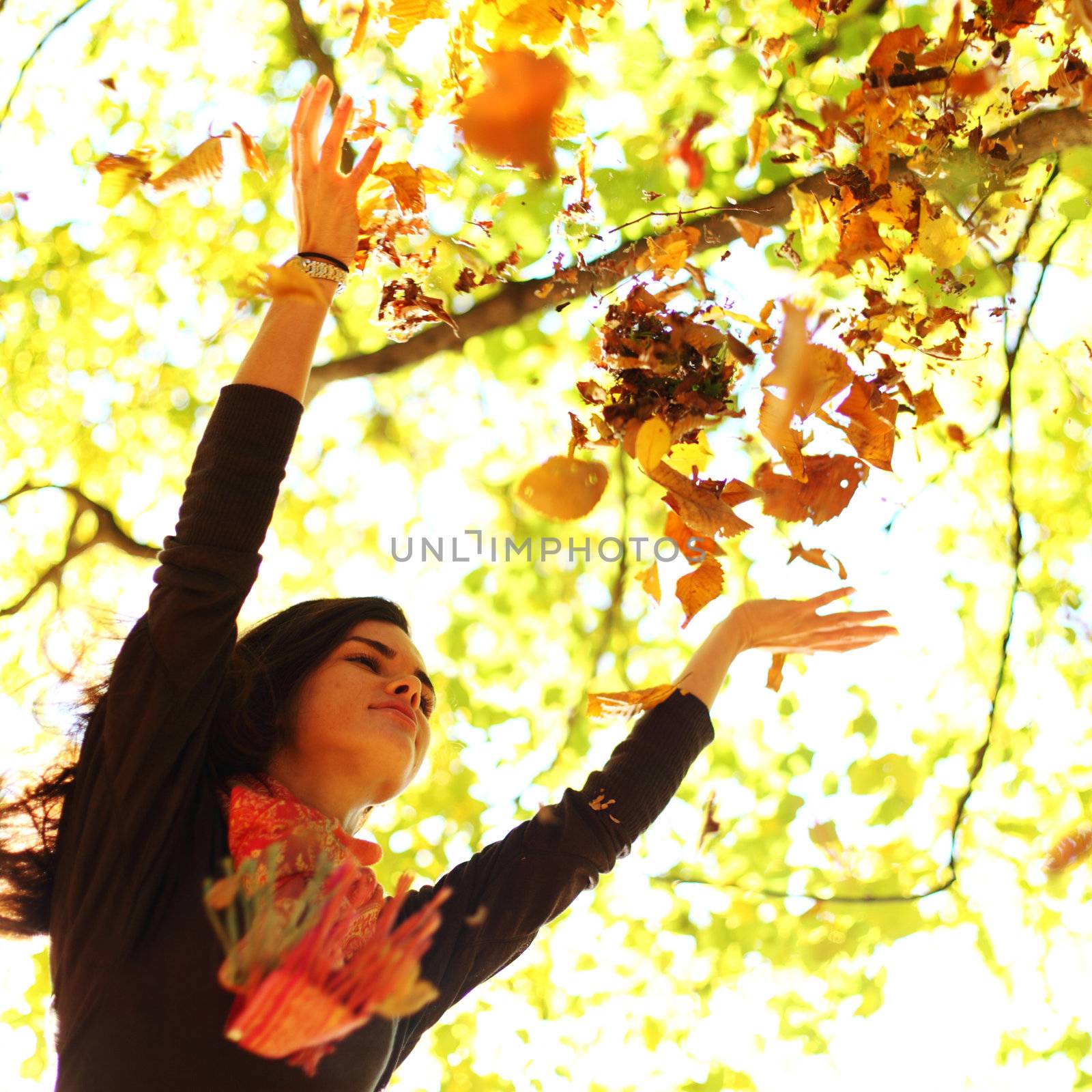 woman drop leaves in autumn park by Yellowj