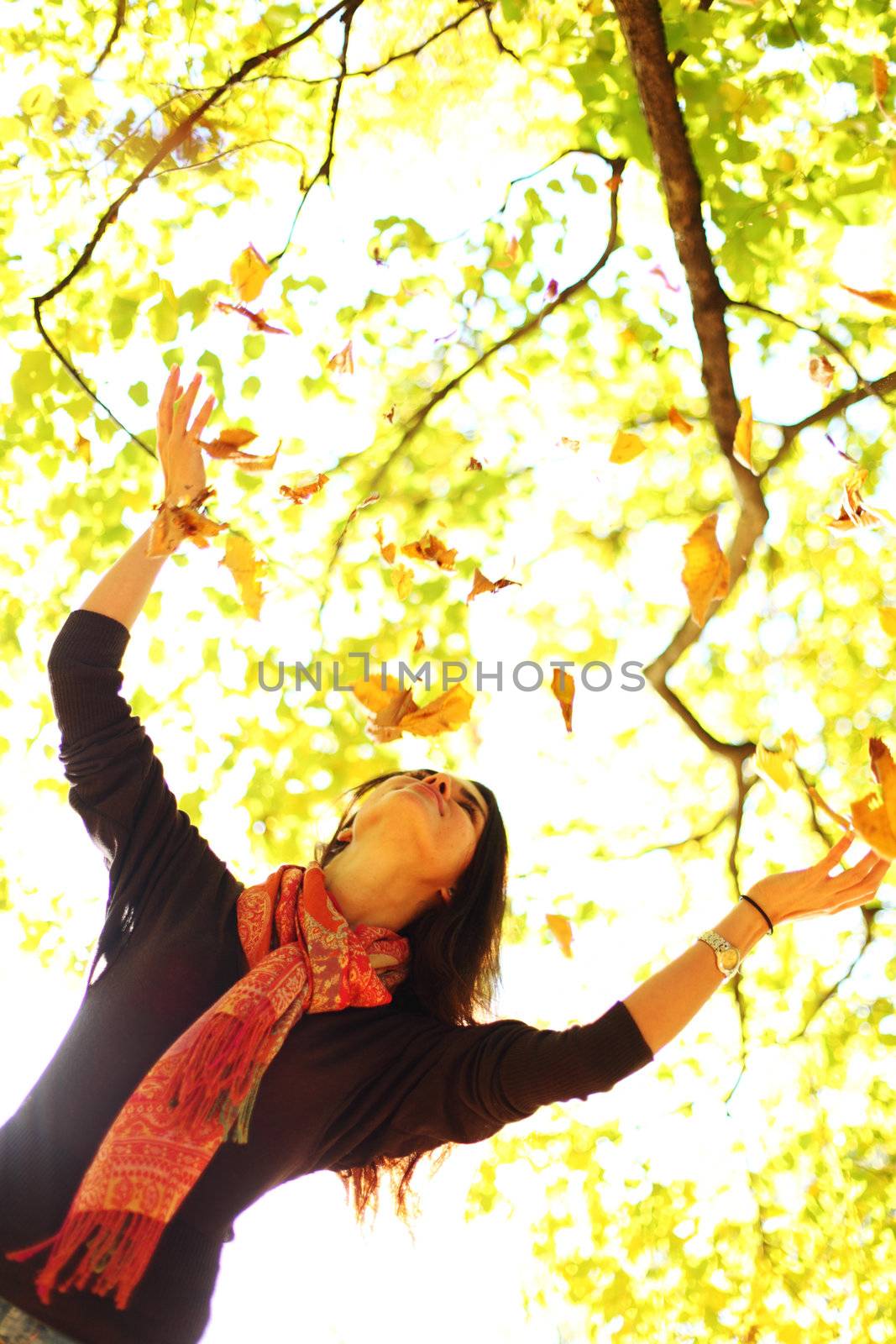 woman drop up leaves in autumn park