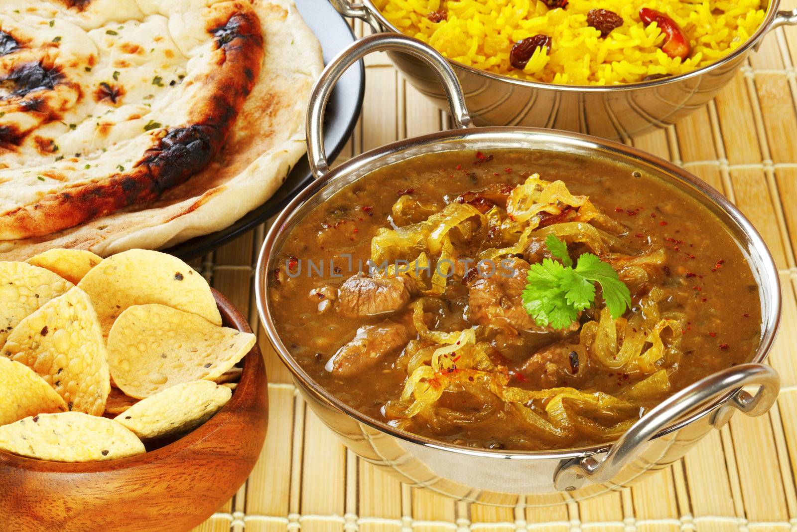 Lamb Dhansak, a tasty curry made with lamb, lentils and vegetables, with poppadums, naan bread, yellow rice.
