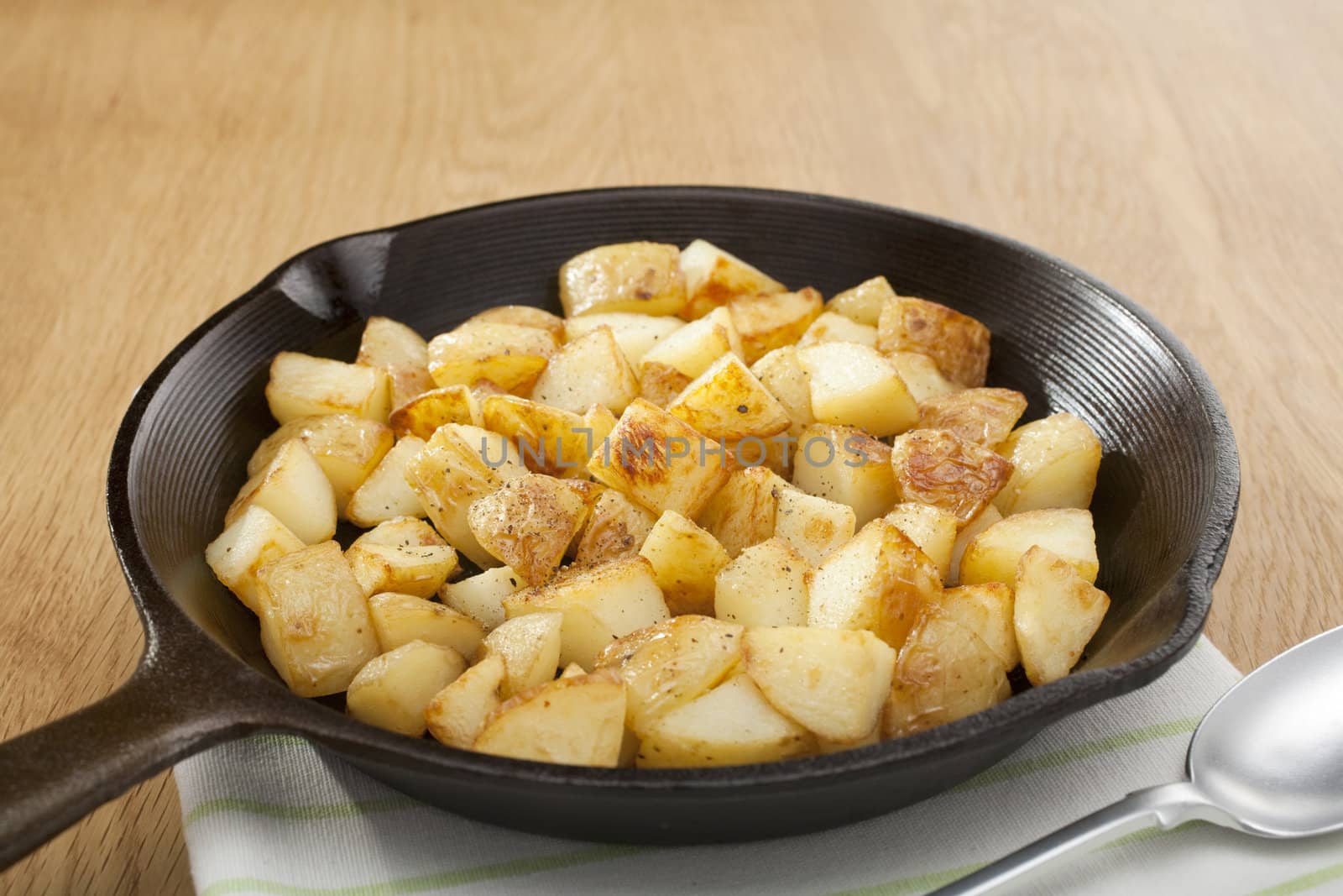 A small cast iron skillet or frying pan filled with home fries or saute potatoes.