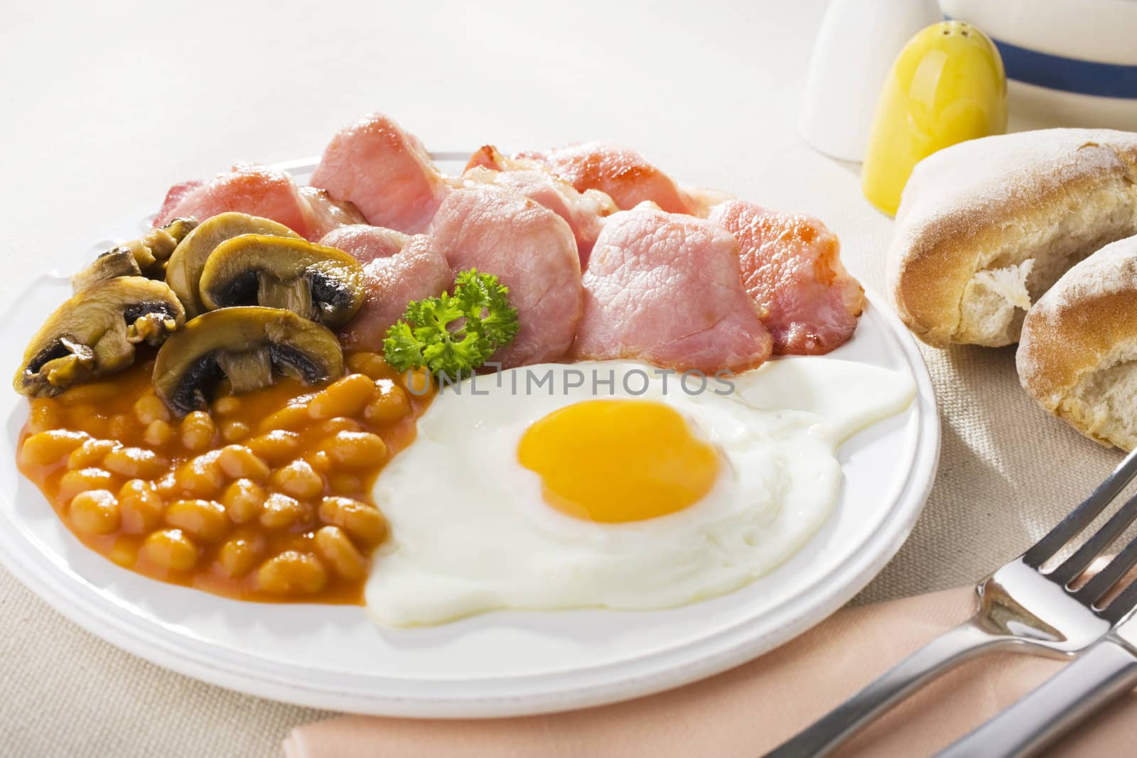 English breakfast of bacon, egg, baked beans and mushrooms.
