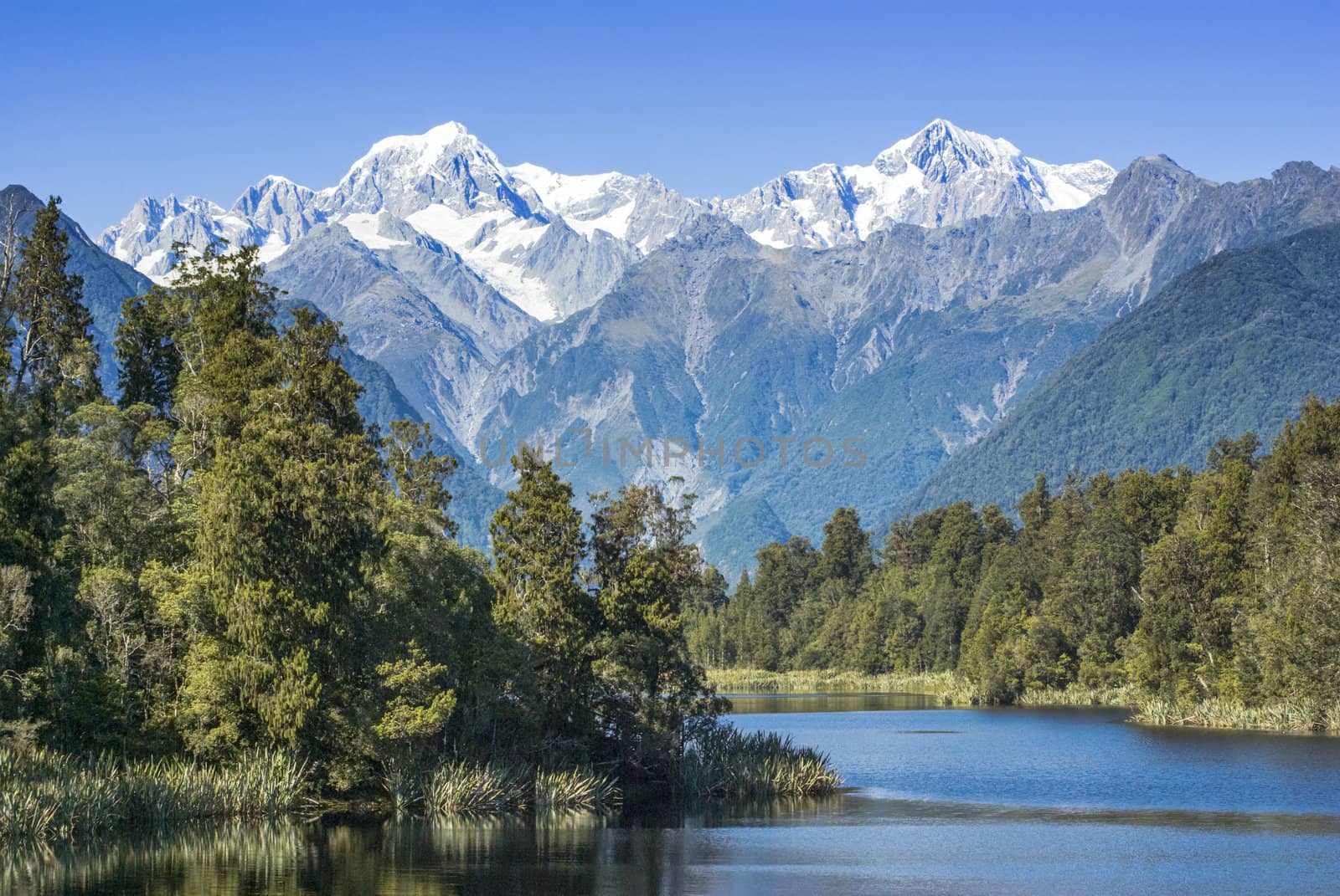 Lake Matheson with snow covered Mount Tasman and Mount Cook, New Zealand's highest mountain. Mount Cook is on the right.