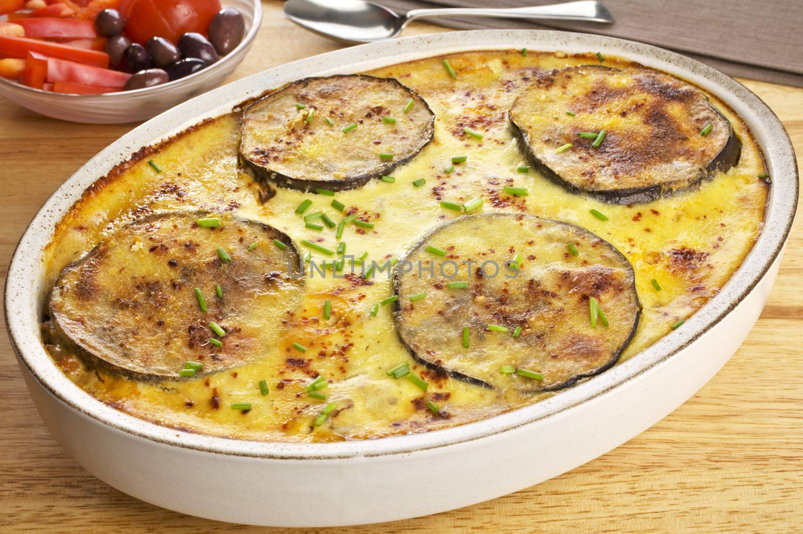 A dish of Moussaka, favourite Greek meal, tasty lamb mince in a sauce with olive oil, garlic, tomato, onion and cinnamon, layered with aubergine and potato, and topped with cheesy, eggy, bechamel sauce. Typical of the Mediterranean diet.