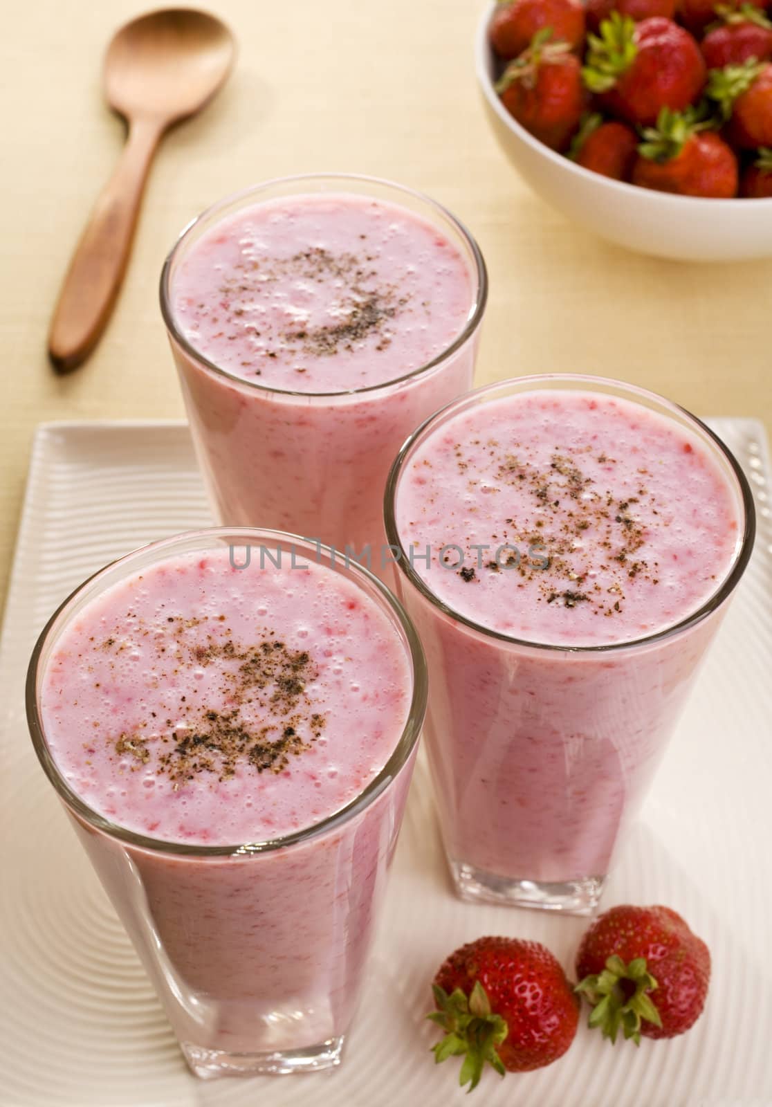 Very light and bright, three glasses of healthy strawberry lassi, an Indian drink made from buttermilk and fresh strawberries.