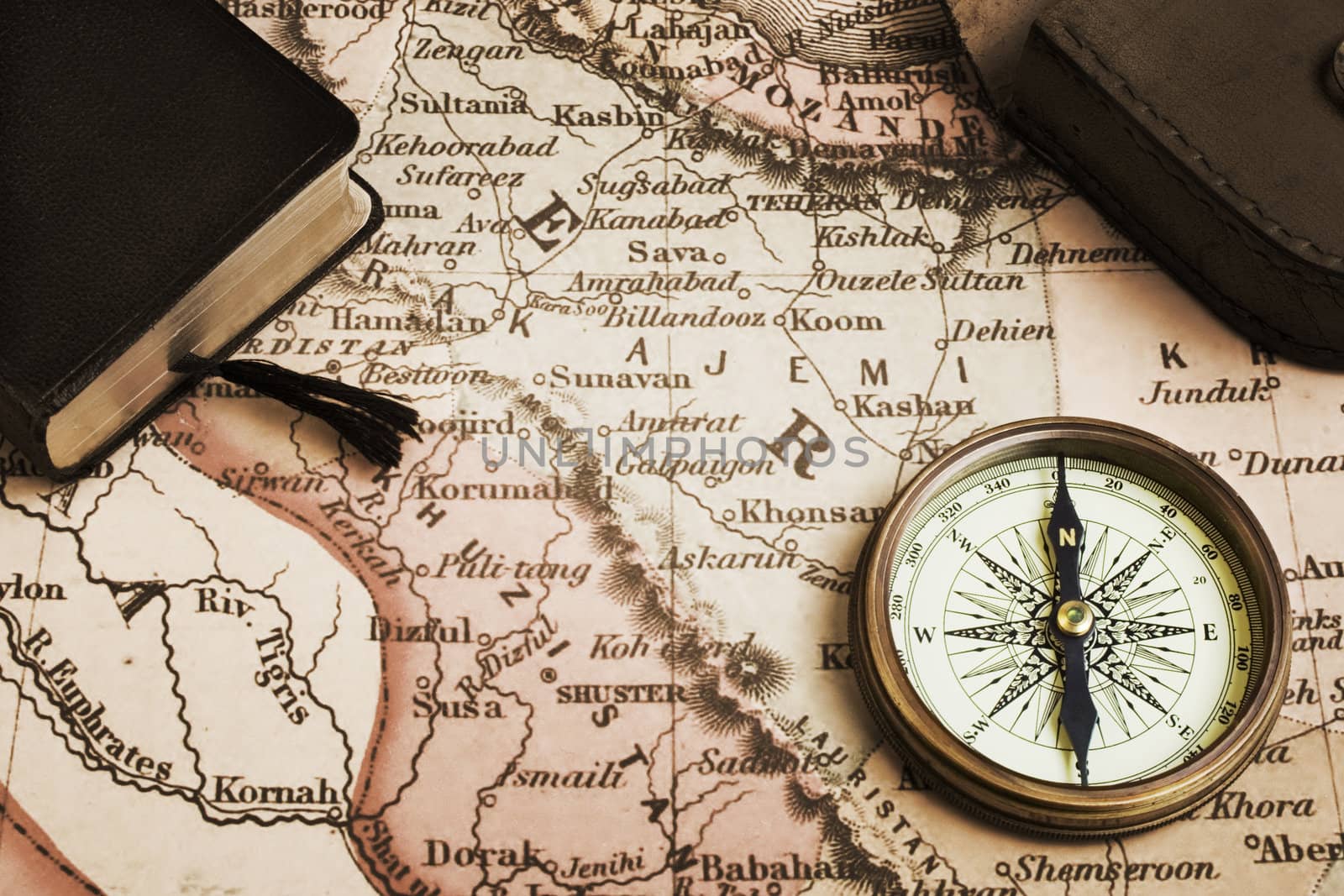 Antique compass with case, book and old map. Concepts of exploration, discovery,adventure,navigation,direction. Monochrome, sepia toned. Map is from 1716 and is out of copyright.