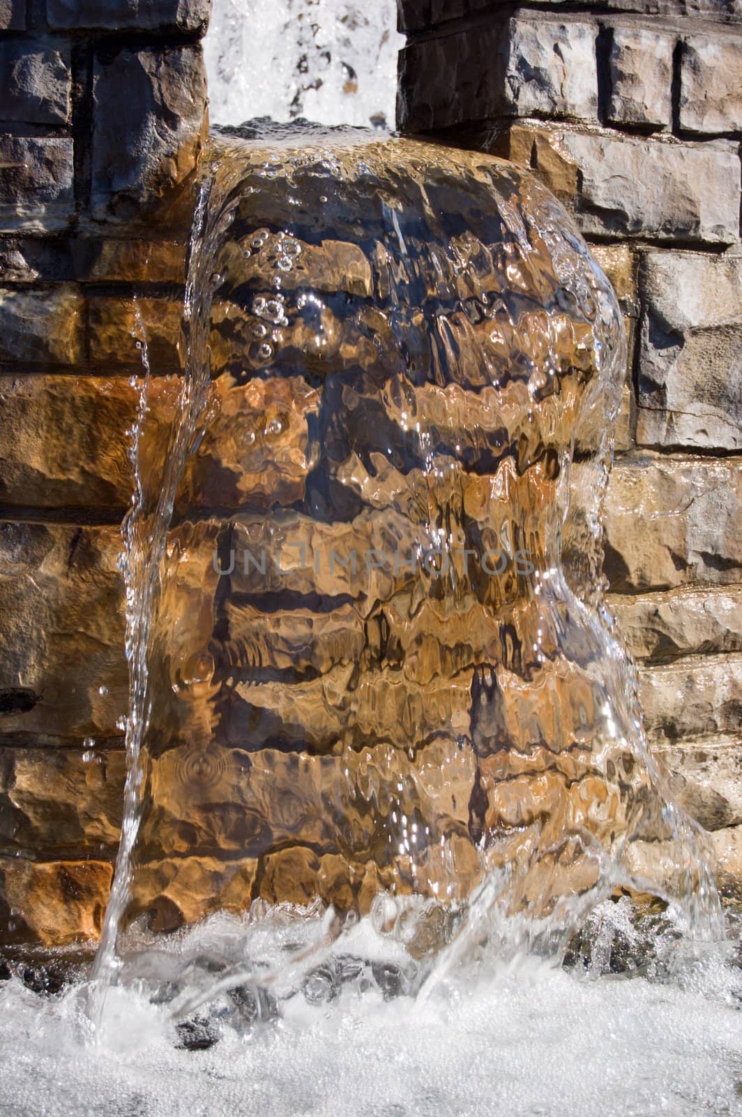 Fountain waterfall in sunlit on stone background
