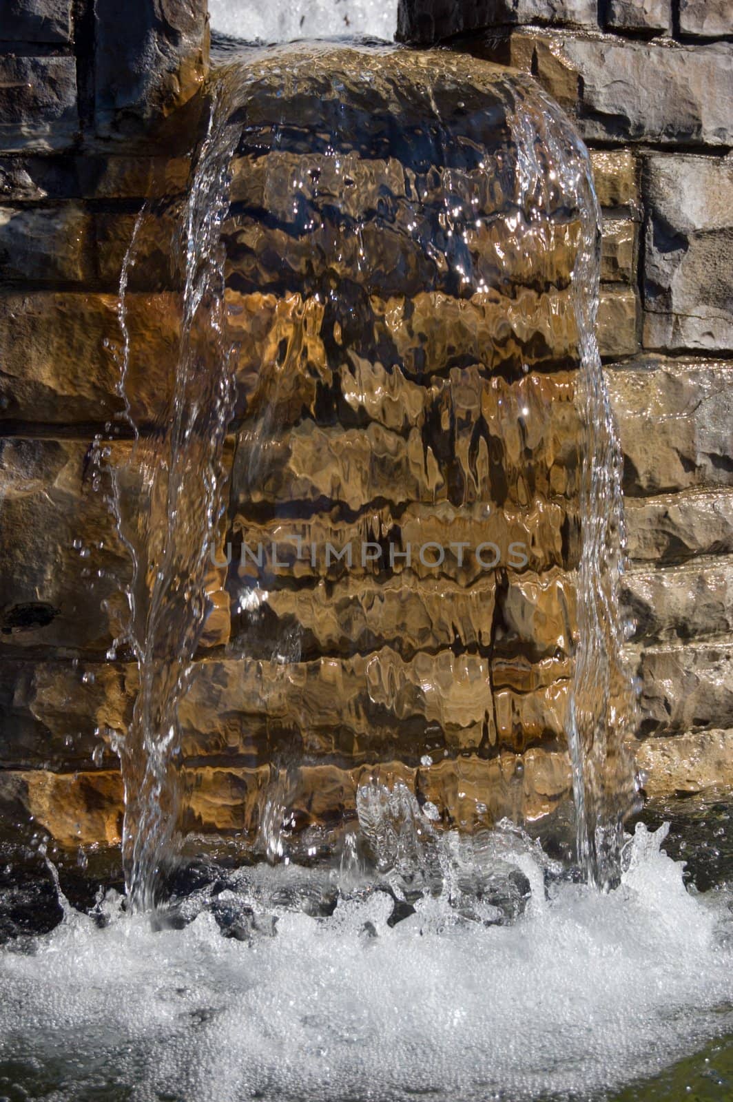 Fountain waterfall in sunlit on stone background