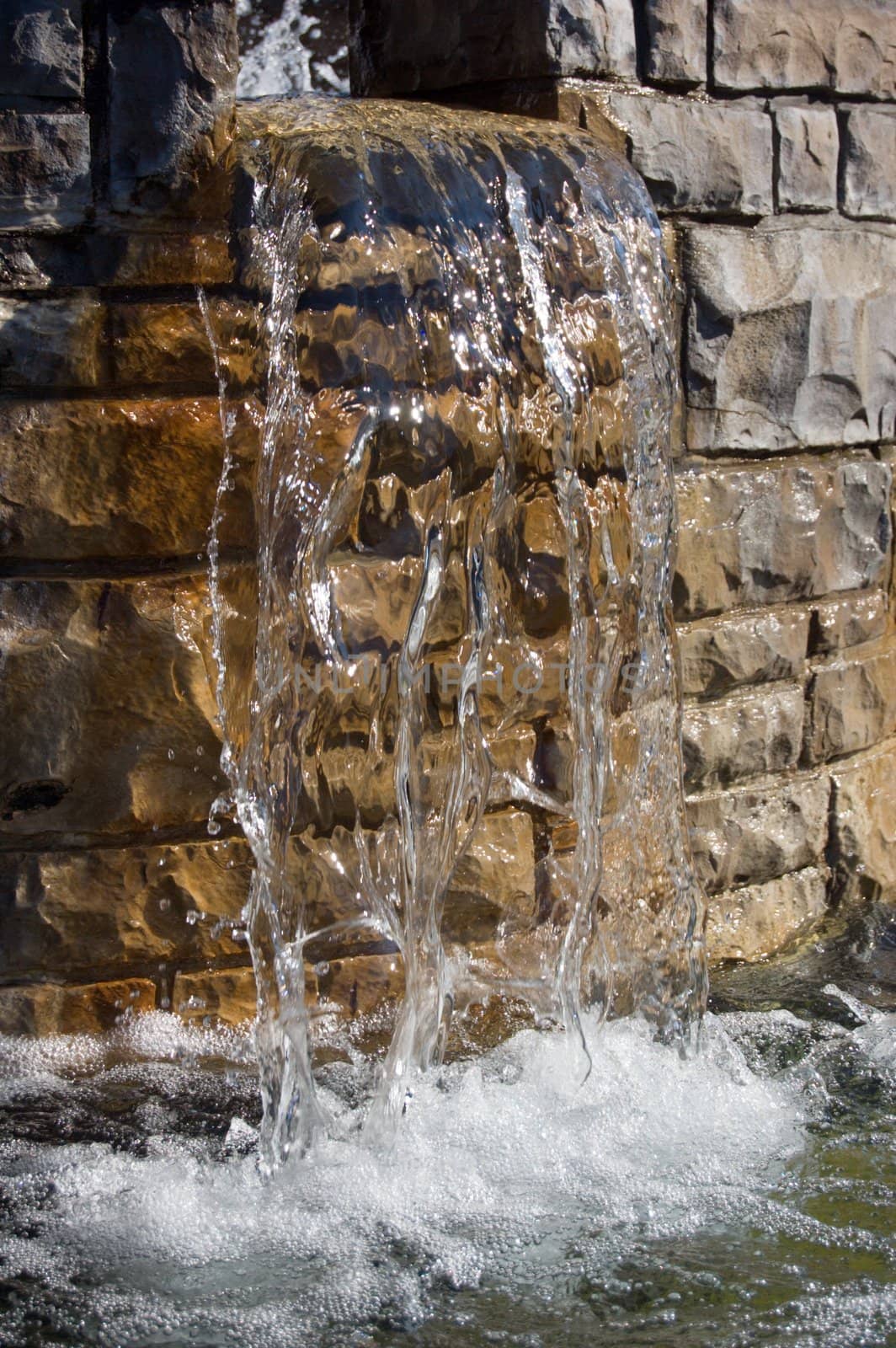 Fountain waterfall in sunlit on stone background