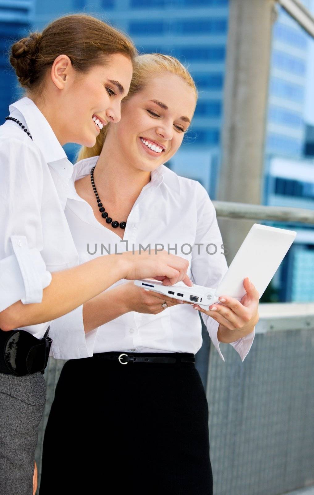 two happy businesswomen with laptop computer (focus on brunette)