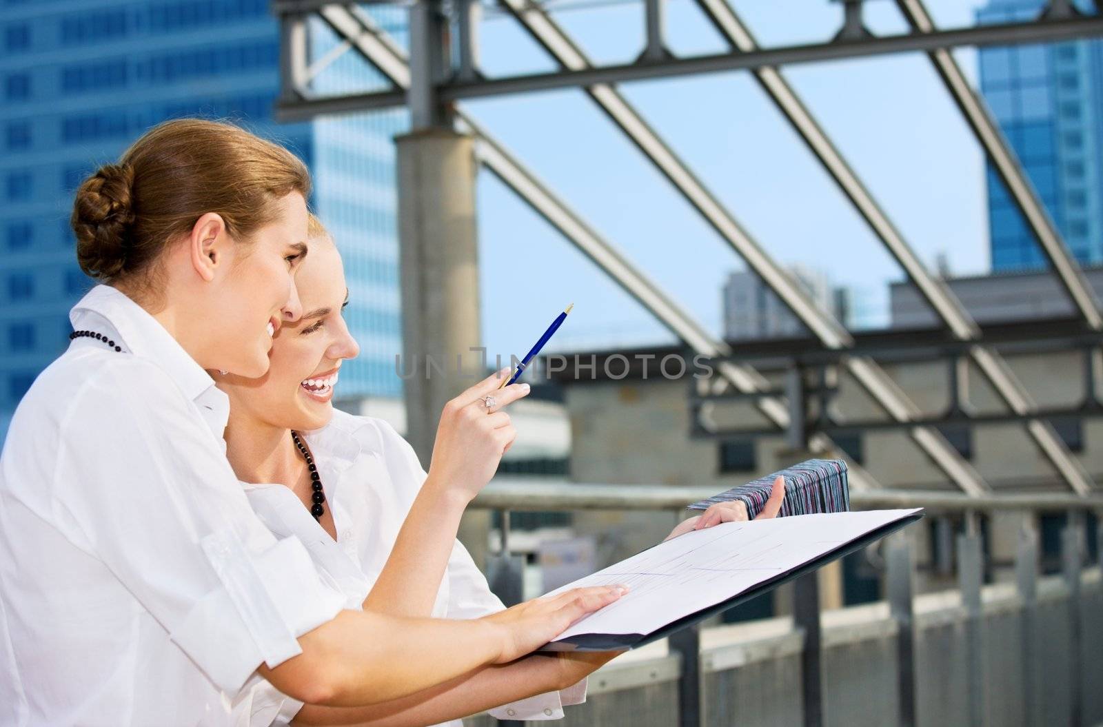 two happy businesswomen with paper chart by dolgachov
