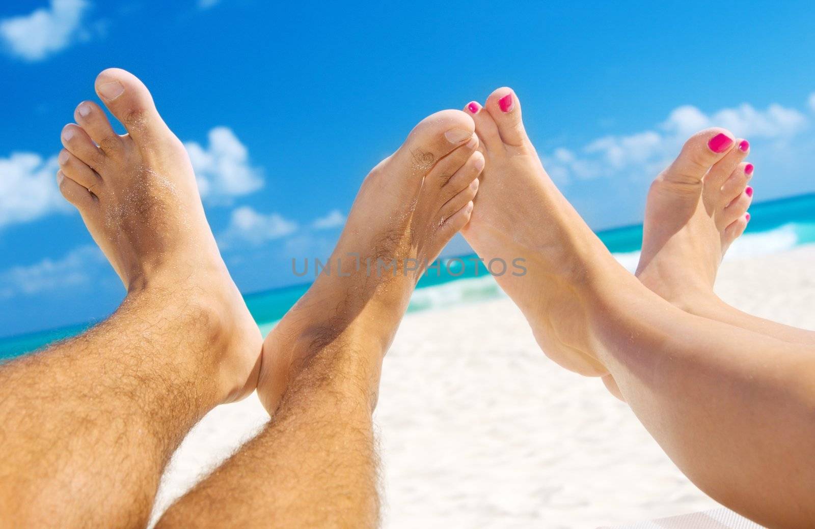 picture of male and female legs over tropical beach background