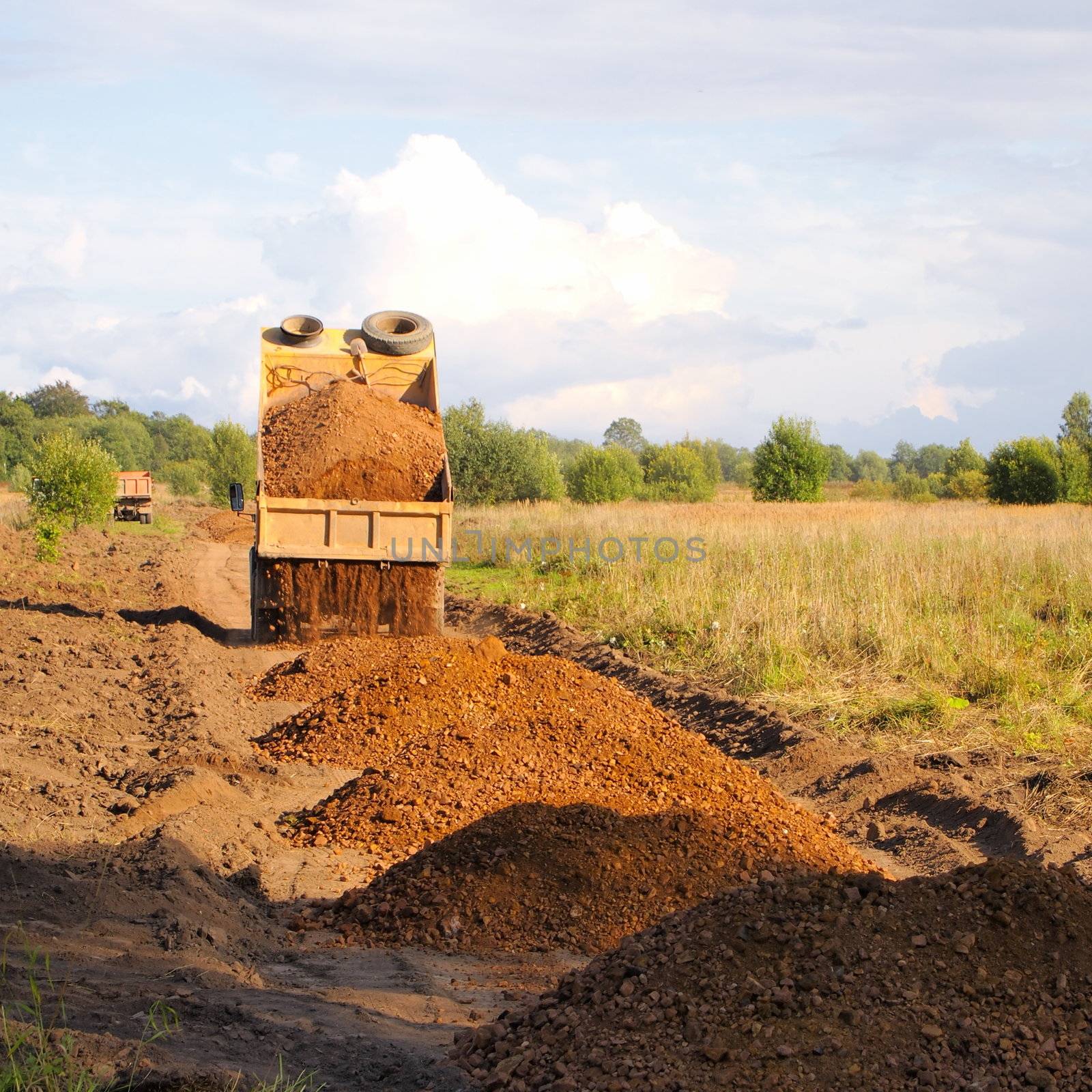 construction of roads, gravel truck unloads