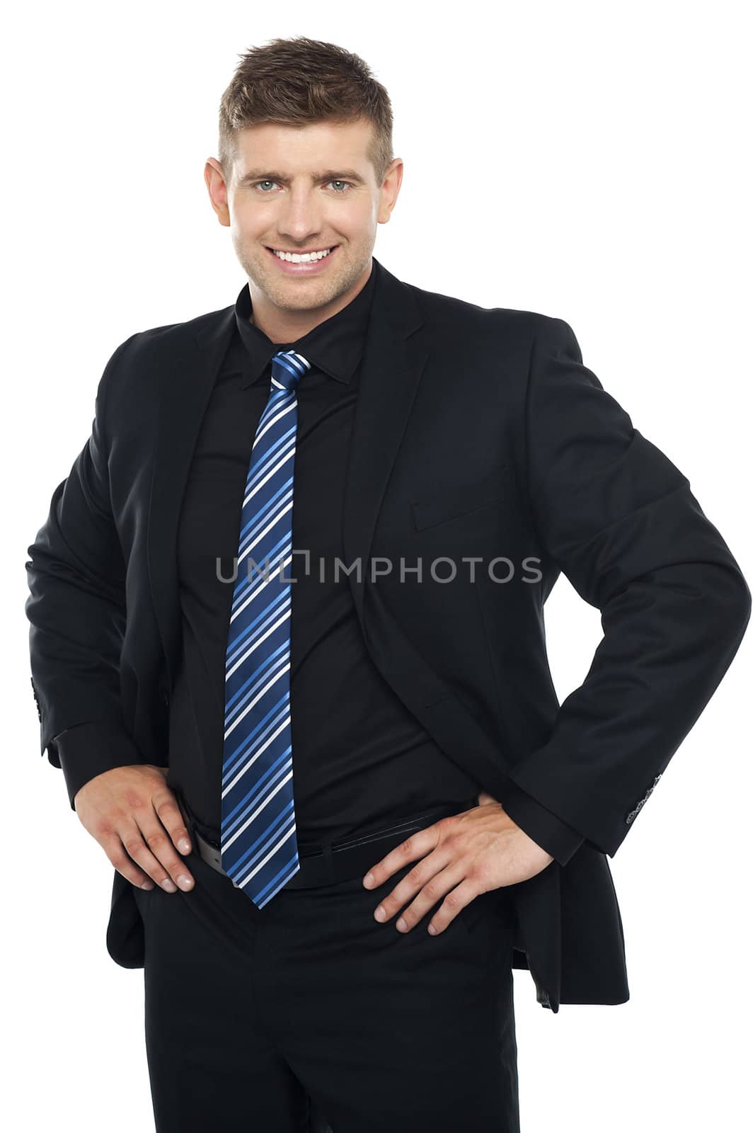 Confident young businessman posing casually. Hands on his waist