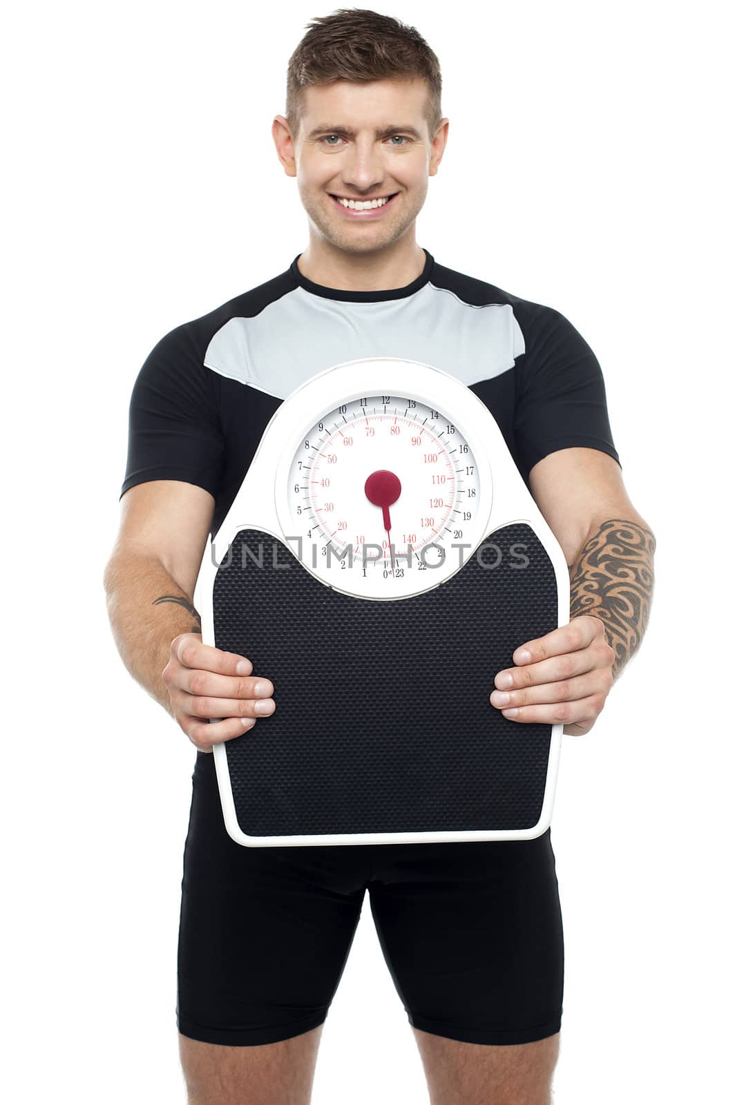 Smart young smiling fit male showing weighing machine to camera