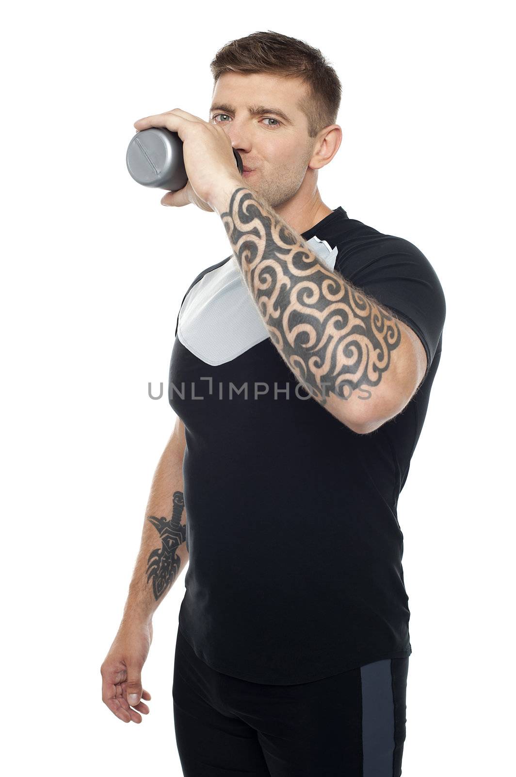 Tired young gym instructor drinking water while looking at you