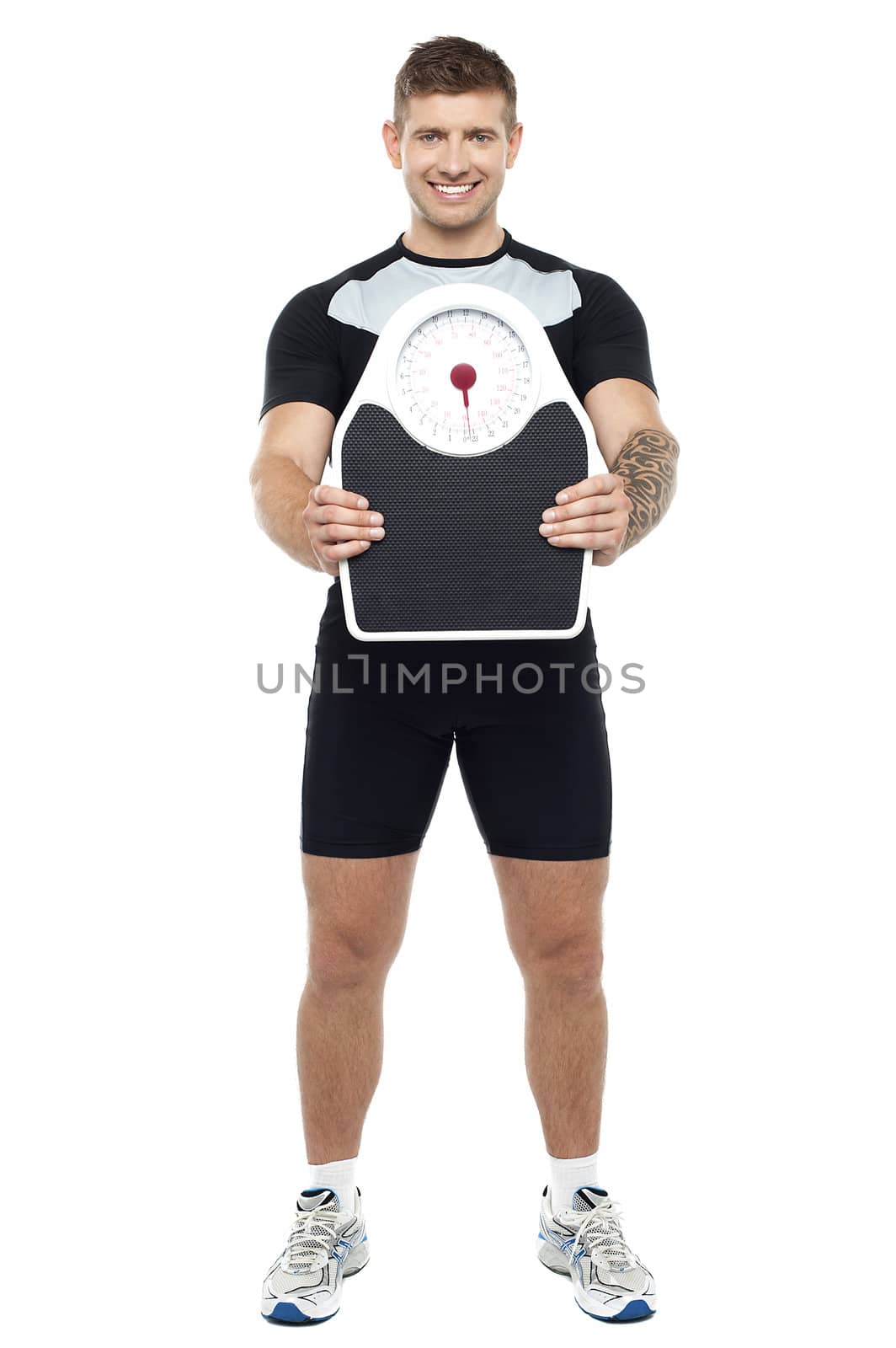 Attractive athlete showing weighing scale against white background