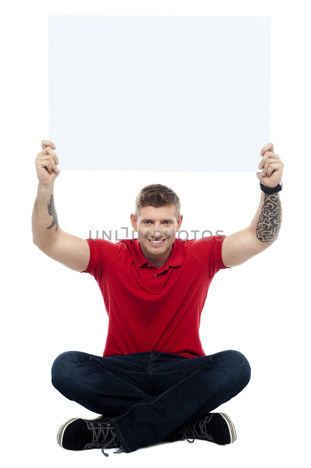 Casual man sitting on floor with billboard raised above head. All over white background