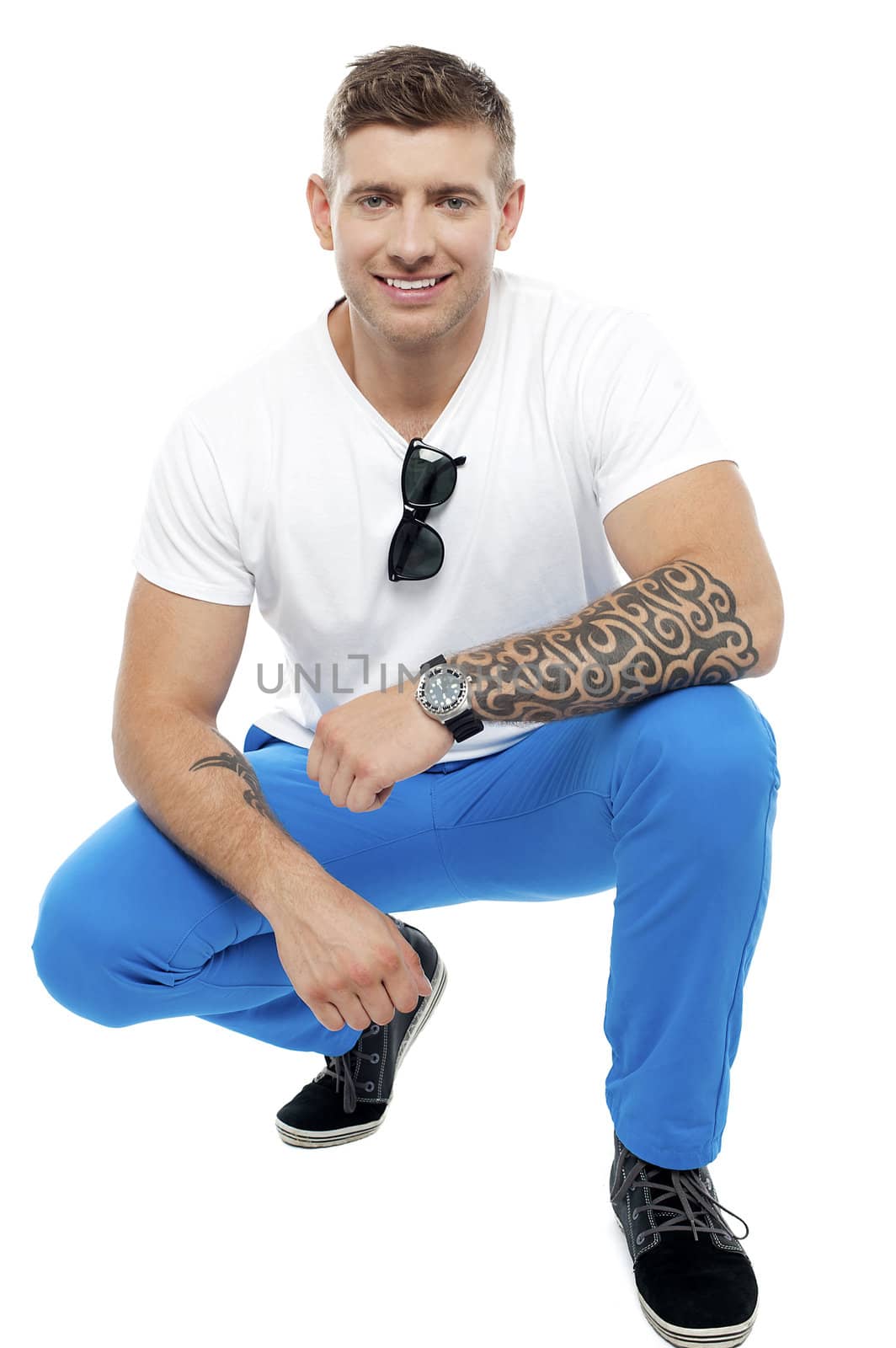 Cheerful young tattooed man in squatting position