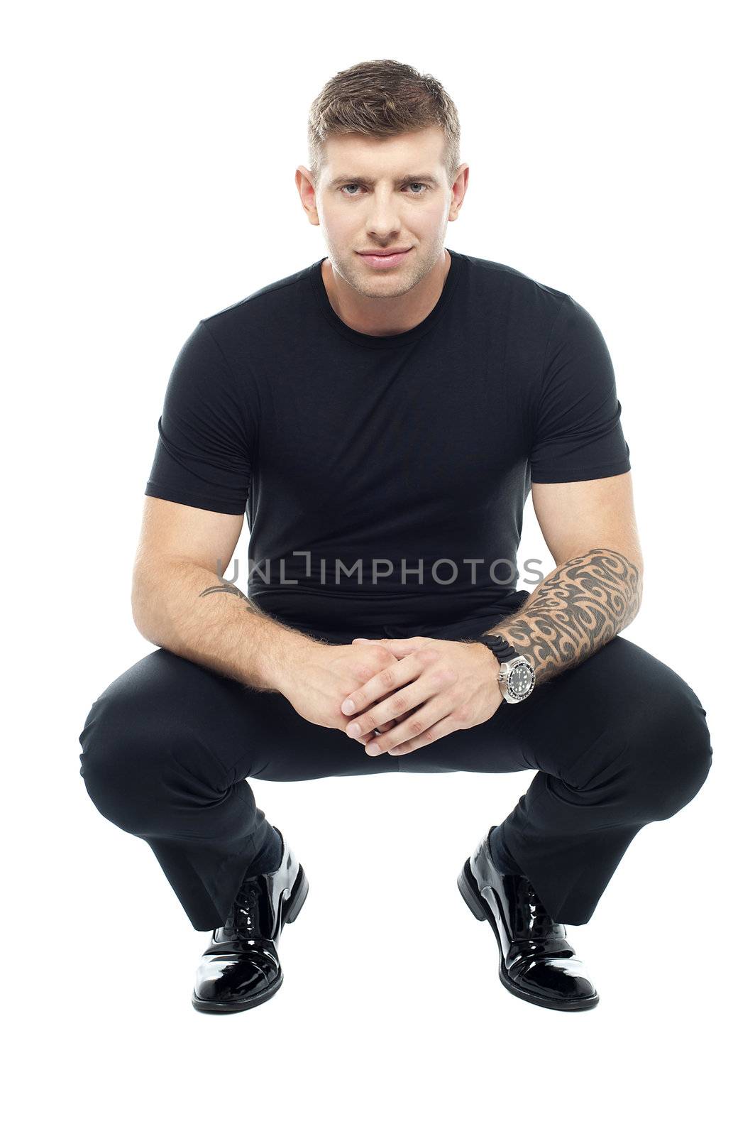 Handsome male bouncer squatting position. Tattoo on his hand