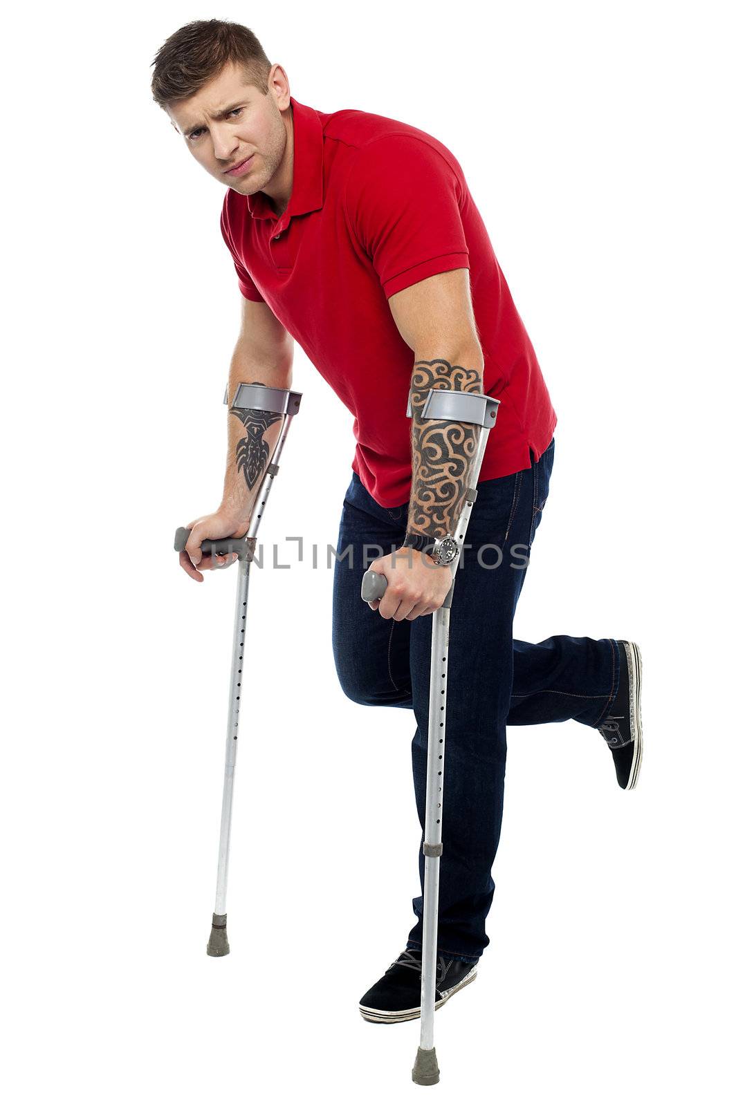 Painful expression of young guy walking with help of crutches. Looking at camera