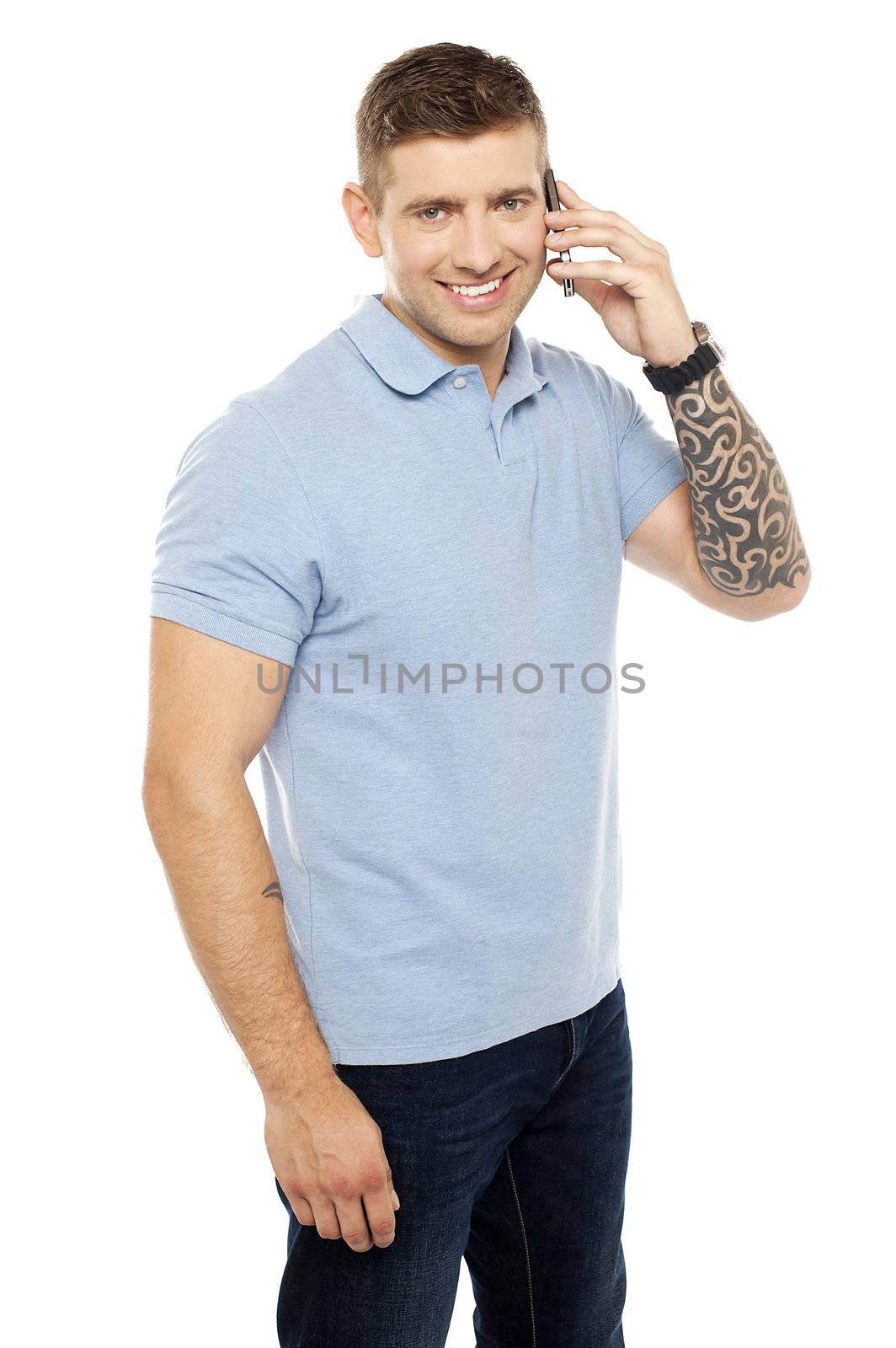 Joyous young chap communicating via cellphone. Creative tattoo drawn on his hand