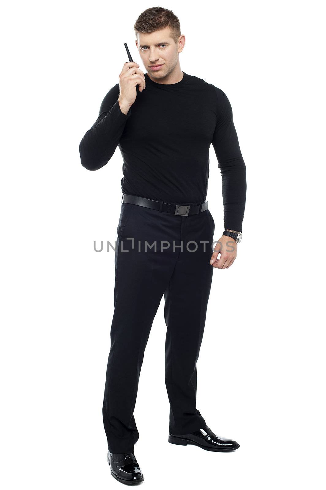 Full length portrait of male bodyguard communicating via walkie-talkie