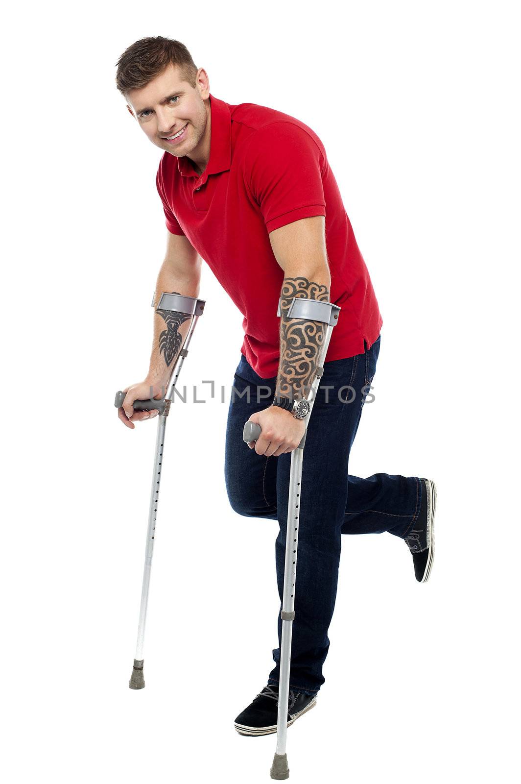 Young man recovering from severe accident. Walking with help of crutches and smiling