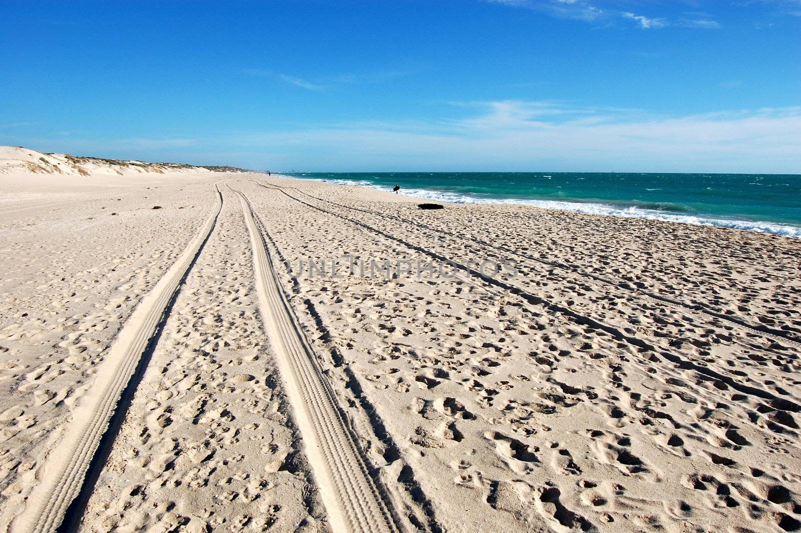 Car track on white sand beach, Australia