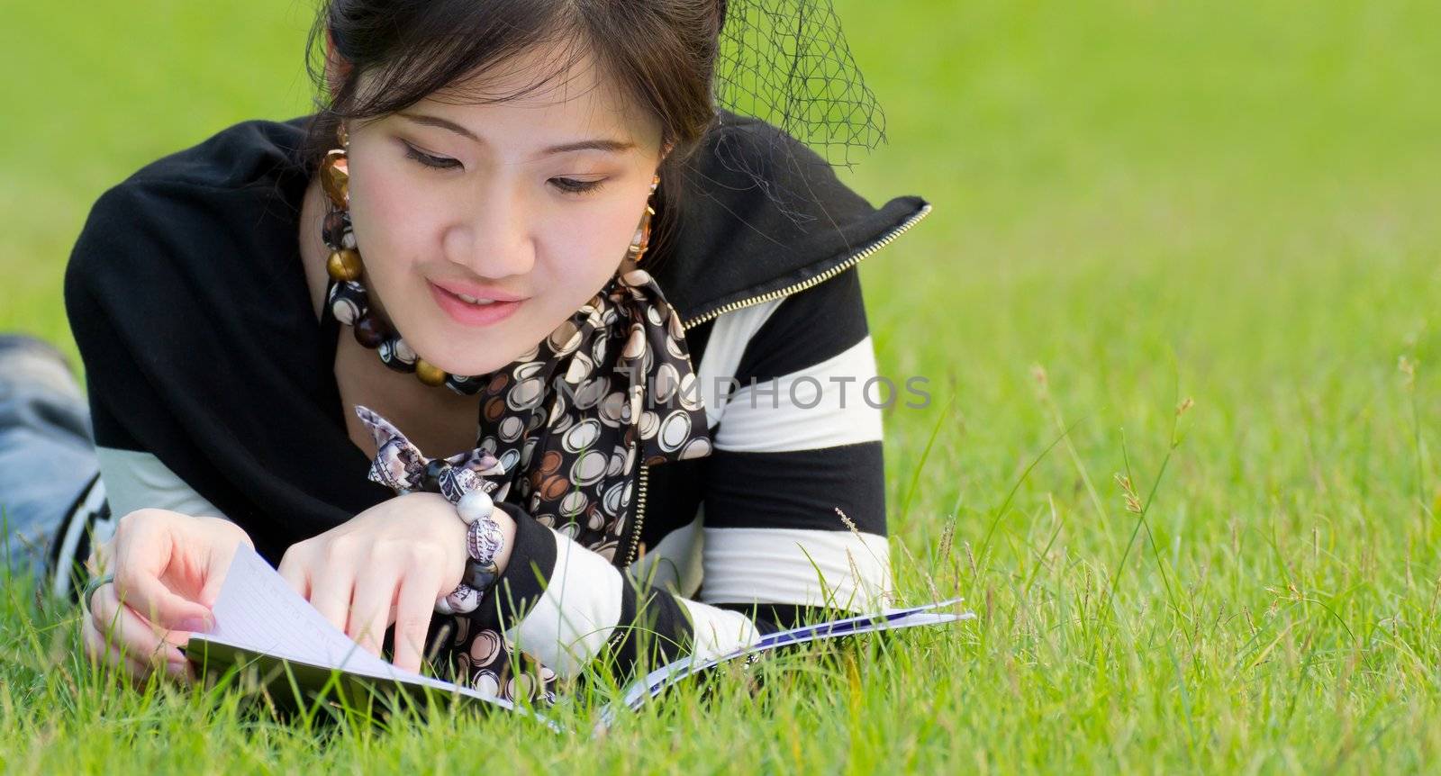 Woman reading book on the grass by Myimagine