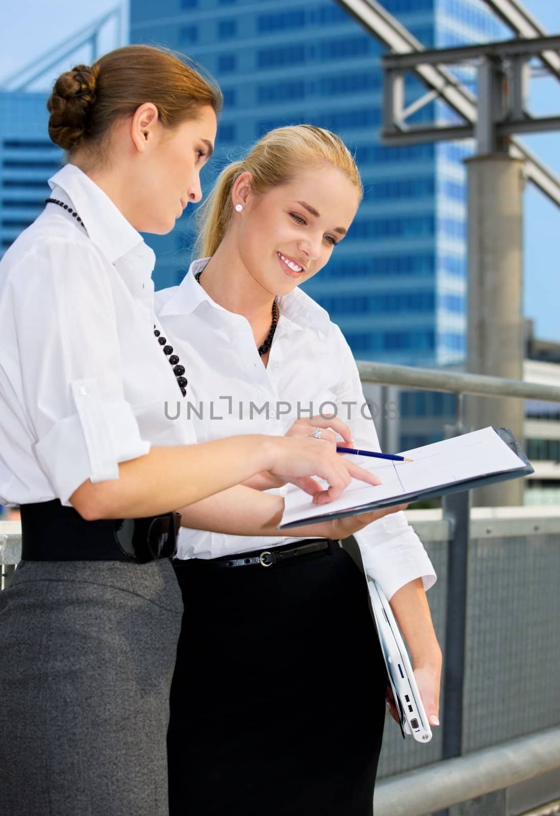 two happy businesswomen with paper chart (focus on blonde)