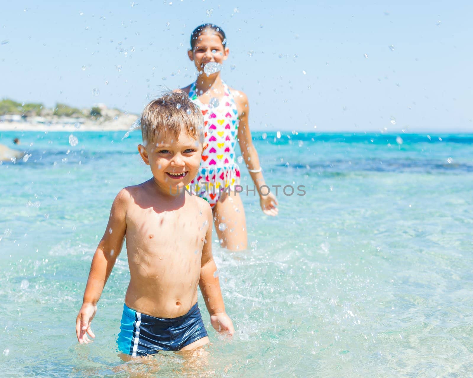 Young sister and brother playing in the transparent sea