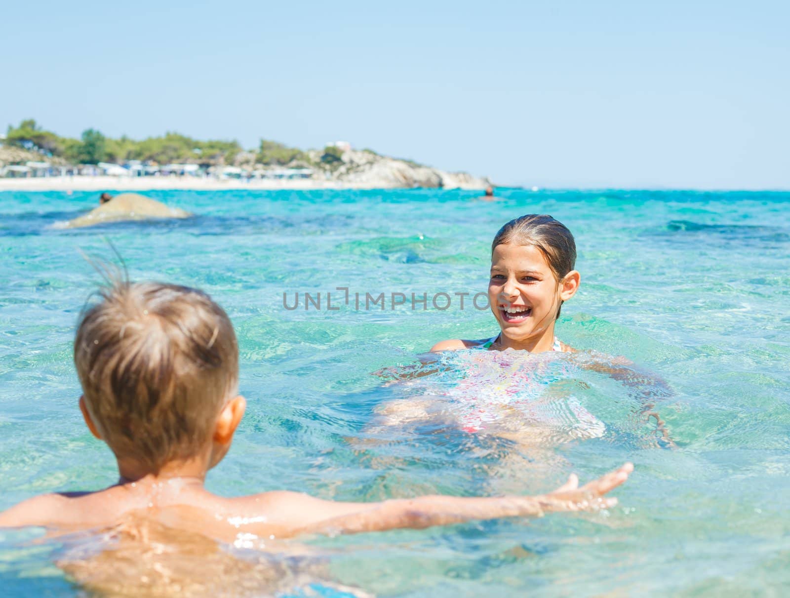 Young sister and brother playing in the transparent sea