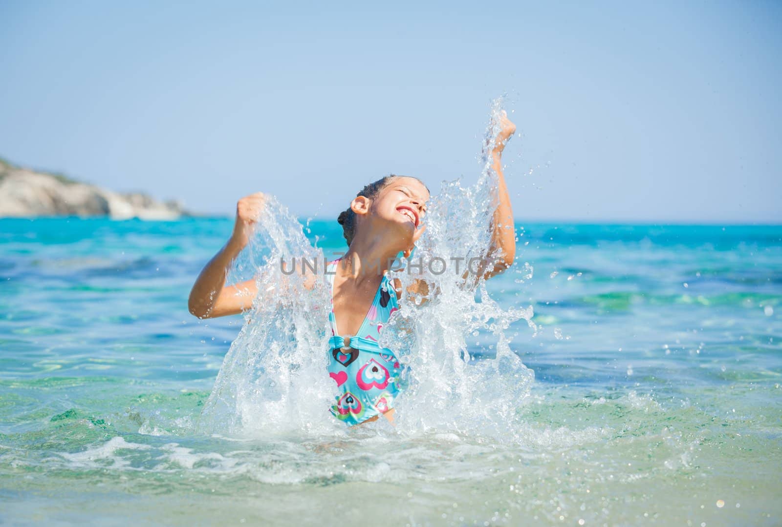 Young girl playing in the wave with spray