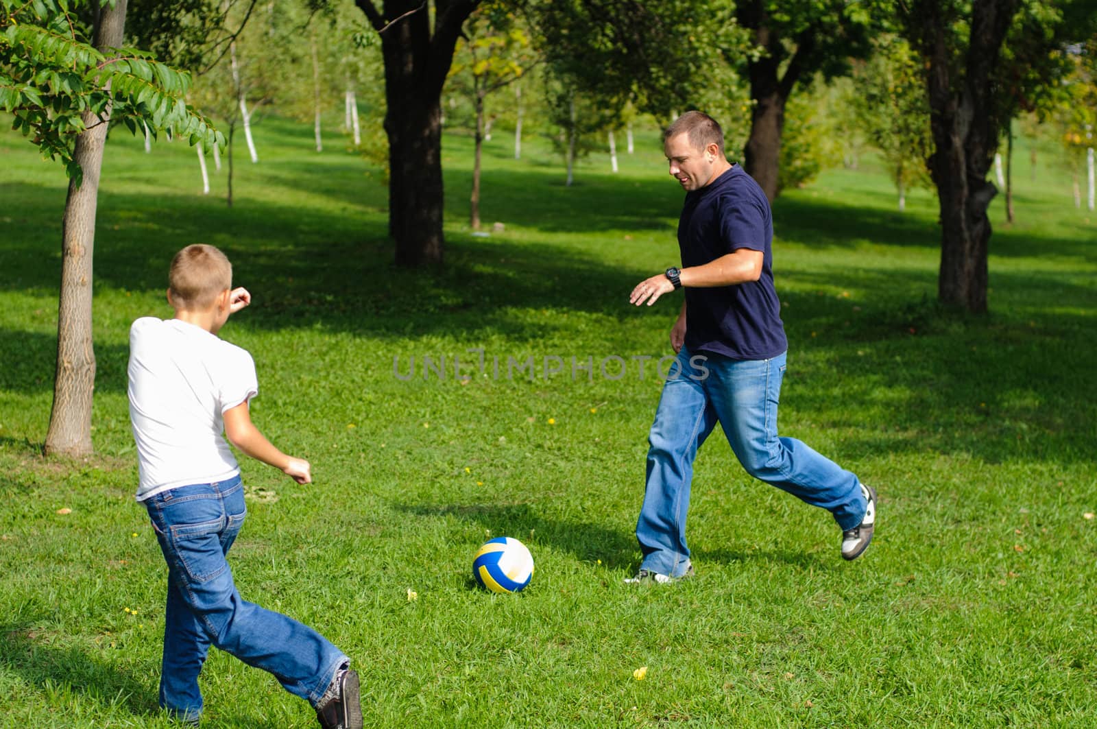 Young boy playing football with his father outdoors